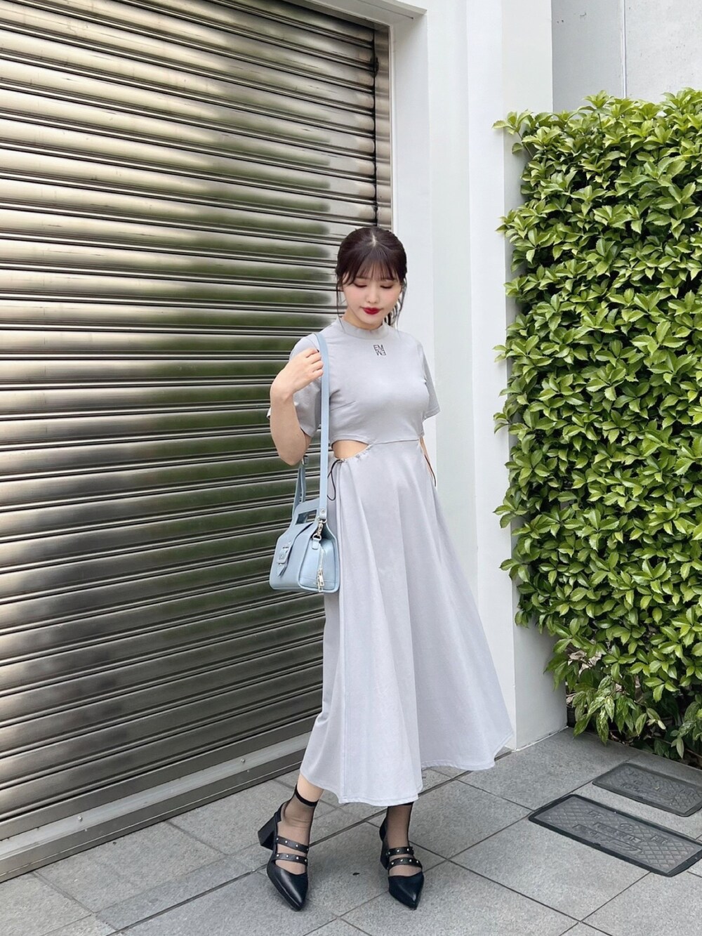 ブルー系のワンピース、ブルー系のハンドバッグ、ブラック系のパンプスを着用したレディースの夏コーディネートの2枚目の写真