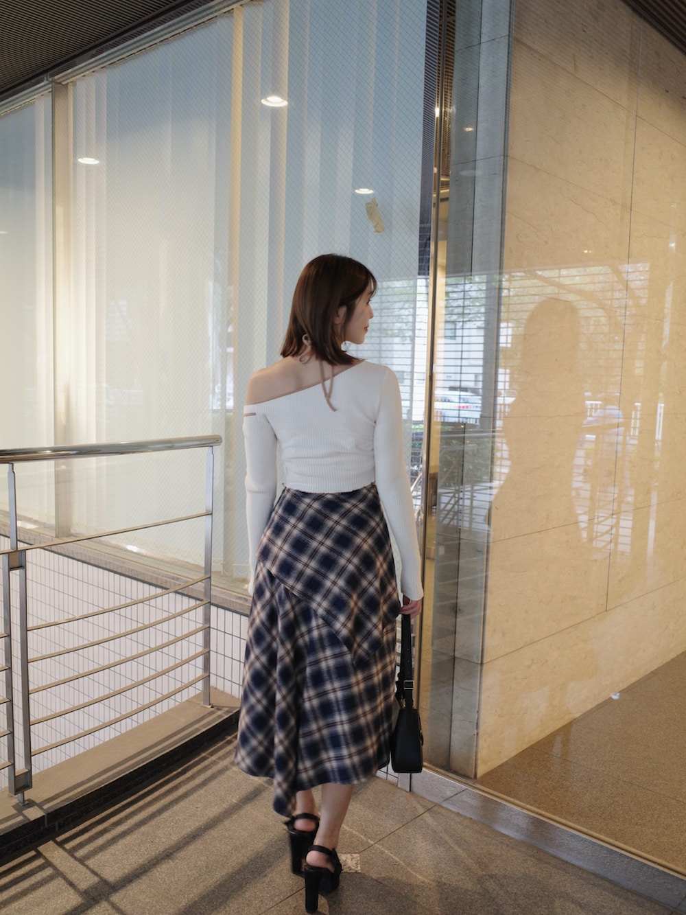 ホワイト系のTシャツ/カットソー、ブルー系のスカート、ブラック系のショルダーバッグを着用したレディースの秋コーディネートの5枚目の写真