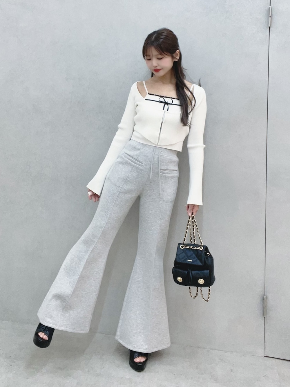 ホワイト系のニット/セーター、グレー系のその他パンツ、ブラック系のバックパック/リュックを着用したレディースの冬コーディネートの2枚目の写真