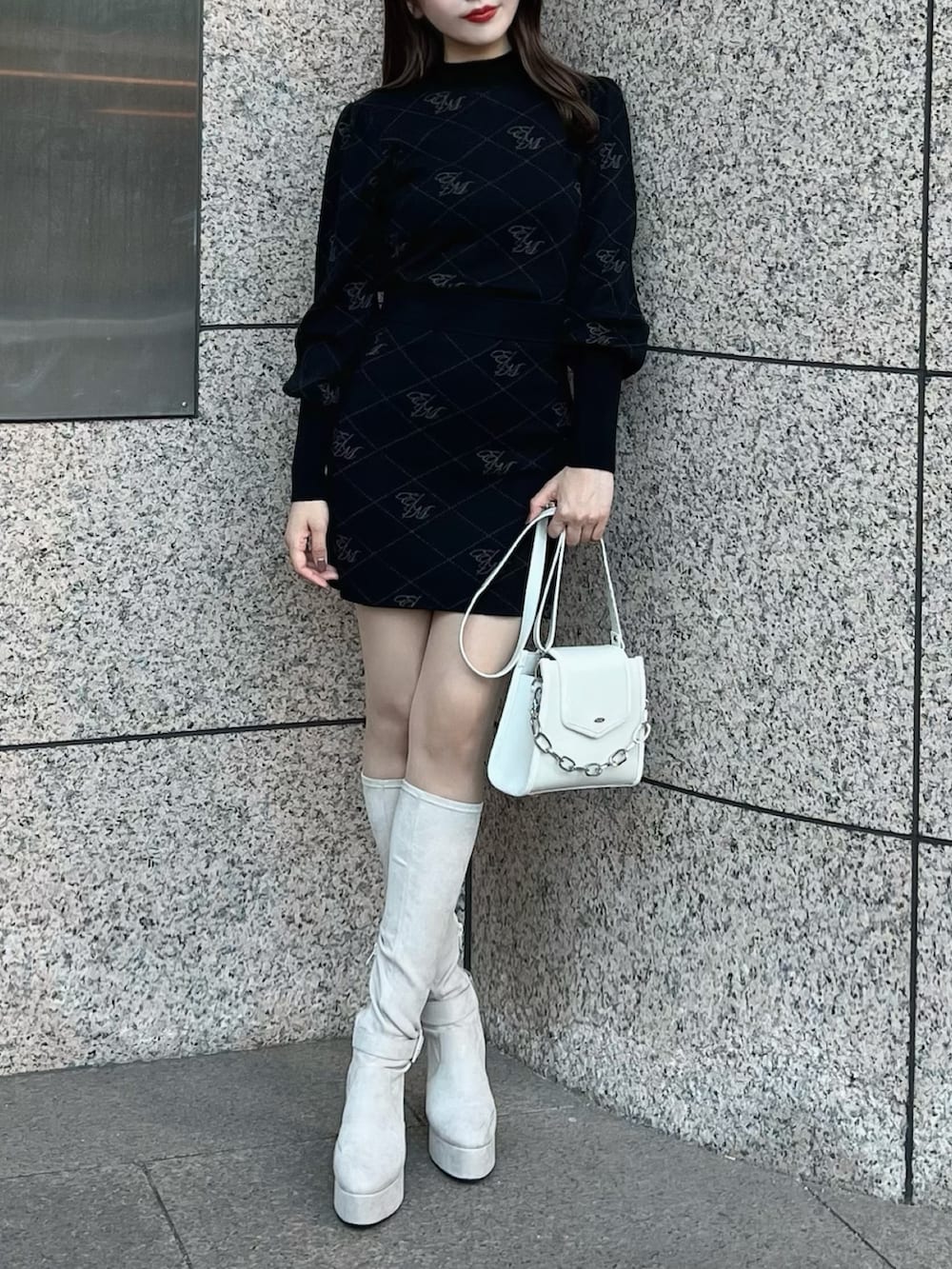 ブラック系のニット/セーター、ホワイト系のブーツ、ブラック系のスカートを着用したレディースの秋コーディネートの2枚目の写真