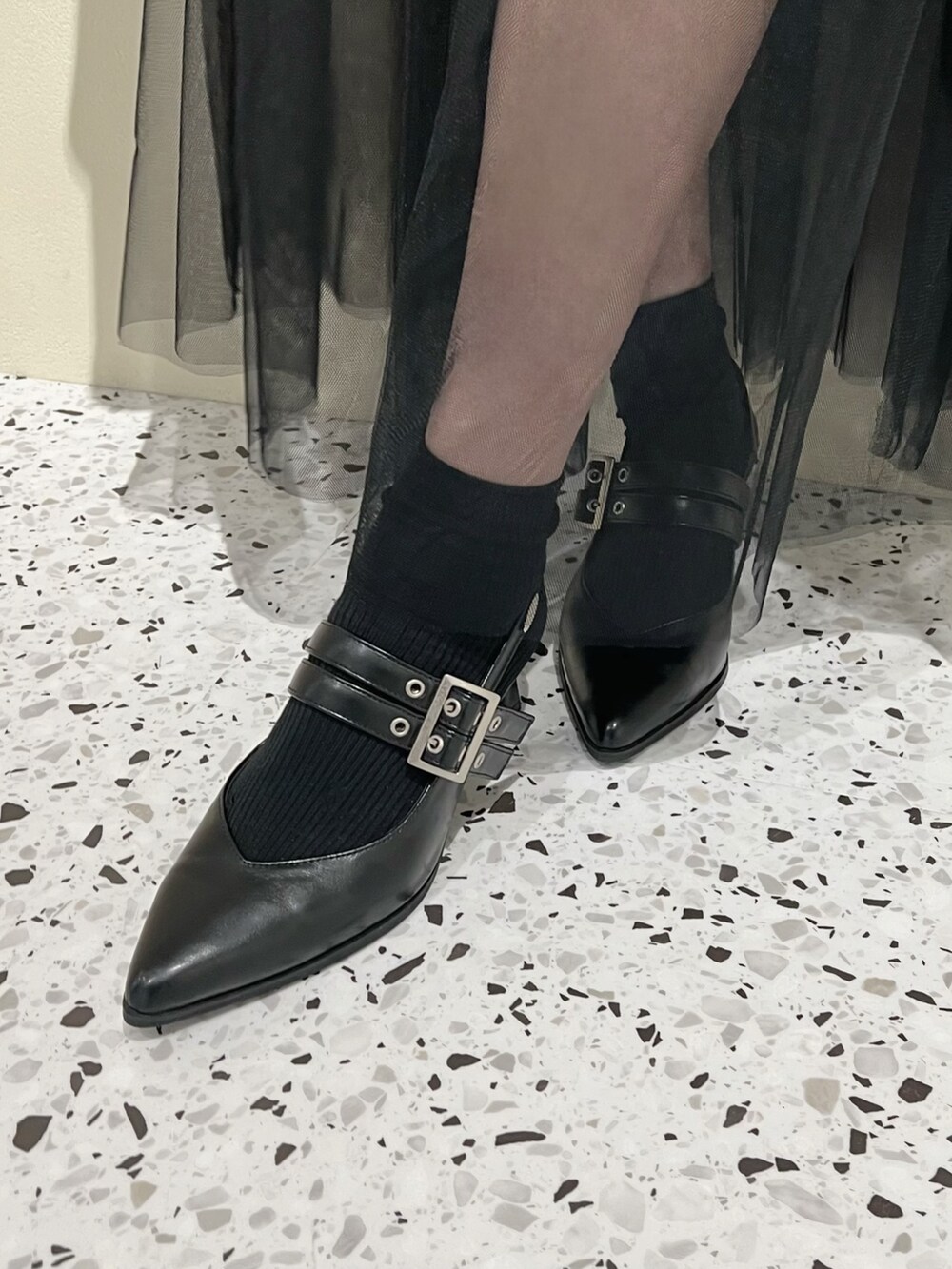 グレー系のニット/セーター、ブラック系のスカート、ブラック系のパンプスを着用したレディースの春コーディネートの6枚目の写真