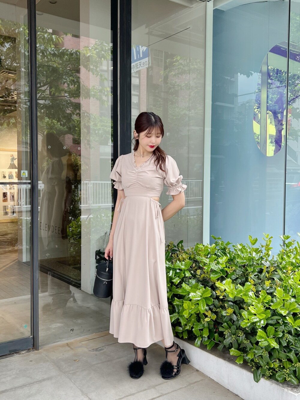 ブラック系のハンドバッグ、ベージュ系のワンピース、ブラック系のサンダルを着用したレディースの春コーディネートの2枚目の写真