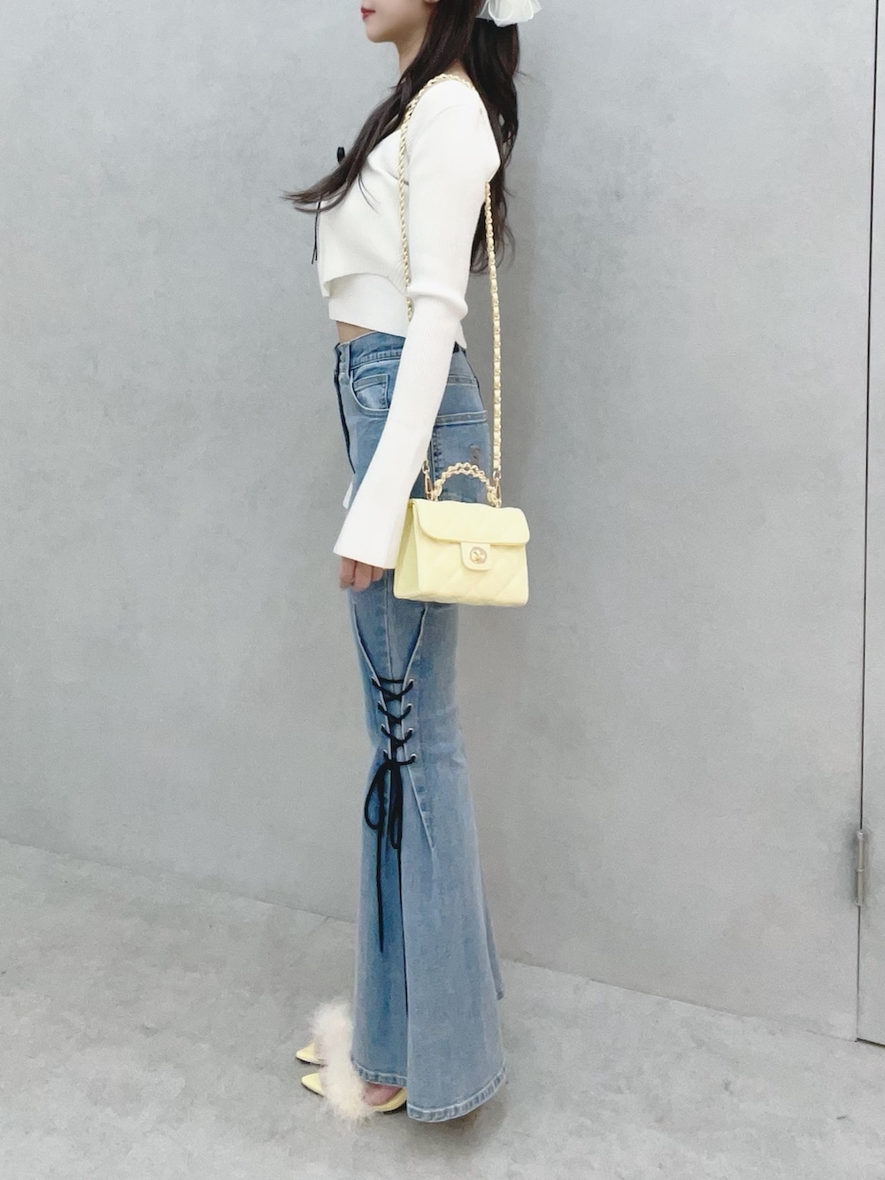 ホワイト系のニット/セーター、イエロー系のサンダル、ブルー系のデニムパンツを着用したレディースの冬コーディネートの4枚目の写真