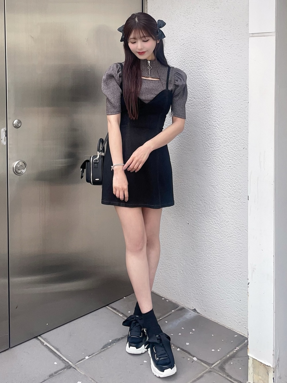 グレー系のニット/セーター、ブラック系のジャンパースカート、その他のサンダルを着用したレディースの春コーディネートの3枚目の写真
