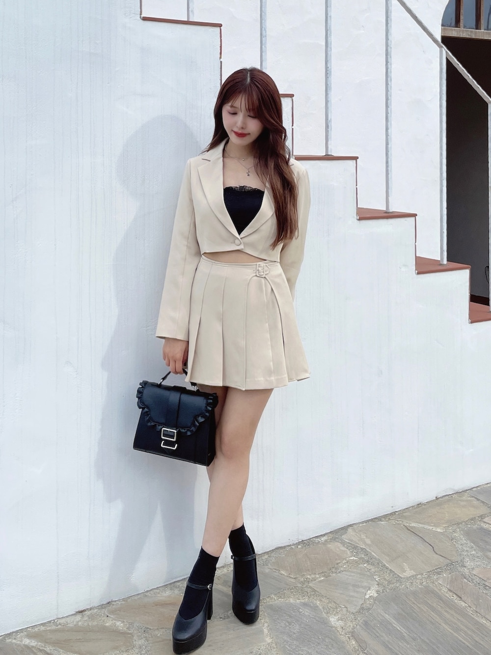 イエロー系のテーラードジャケット、イエロー系のスカート、ブラック系のパンプスを着用したレディースの冬コーディネートの2枚目の写真