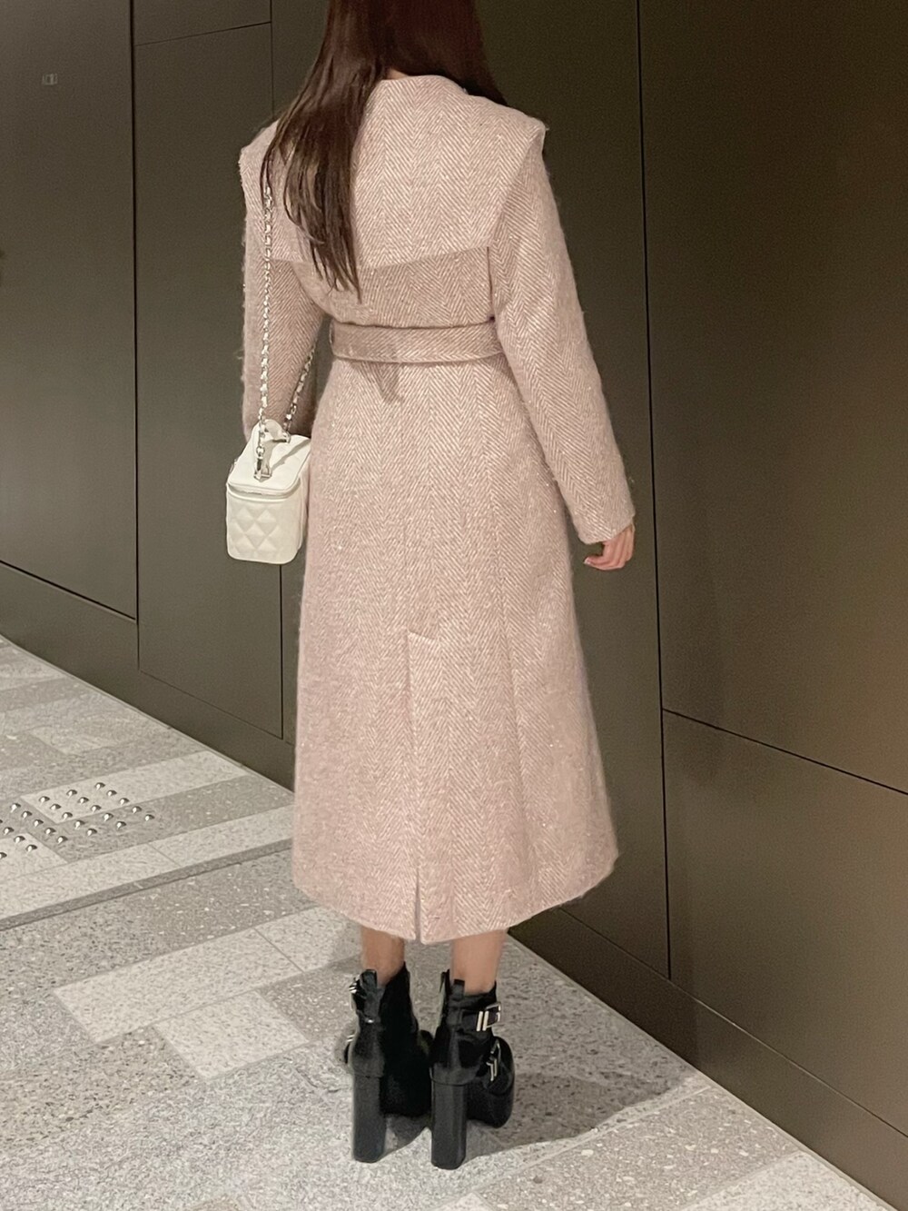 ホワイト系のハンドバッグ、ピンク系のチェスターコート、ブラック系のブーツを着用したレディースの冬コーディネートの4枚目の写真