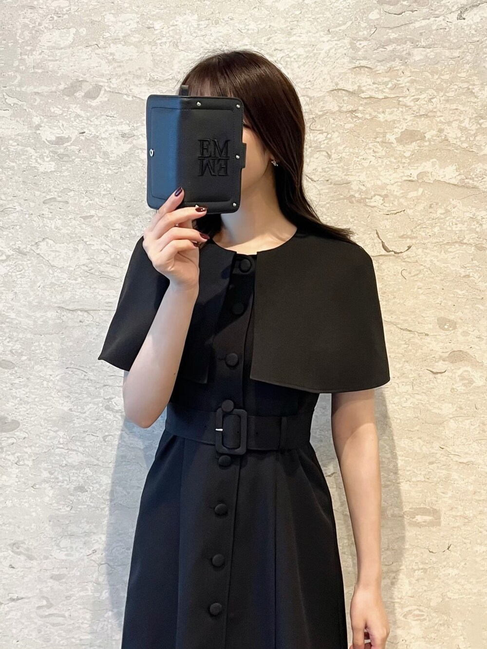 ブラック系のワンピース、ブラック系のサンダル、ホワイト系のショルダーバッグを着用したレディースの夏コーディネートの2枚目の写真