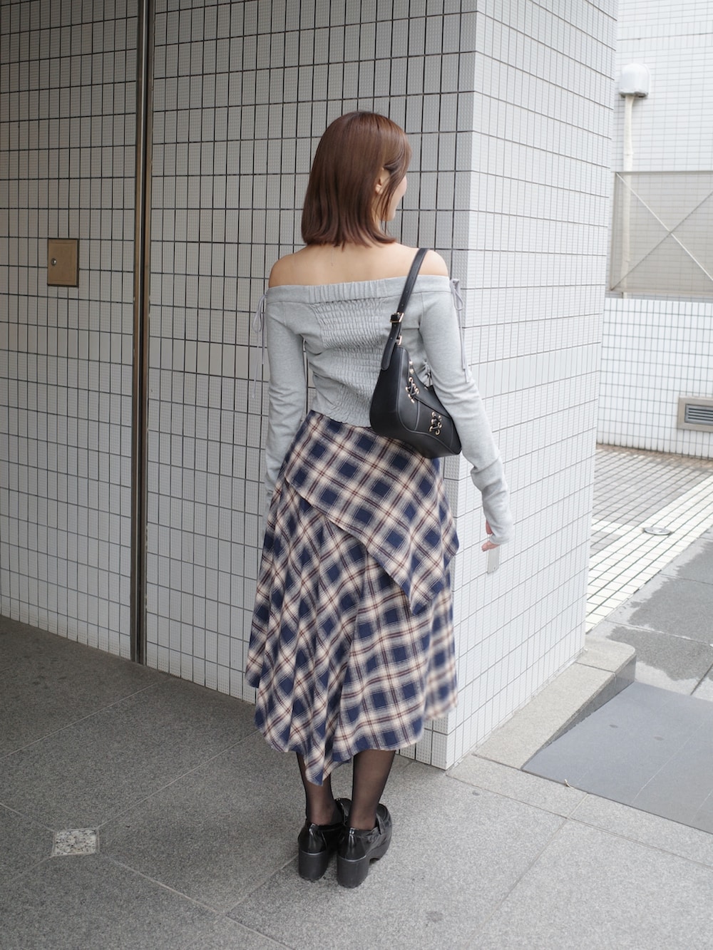 グレー系のTシャツ/カットソー、ブルー系のスカート、ブラック系のショルダーバッグを着用したレディースの秋コーディネートの4枚目の写真