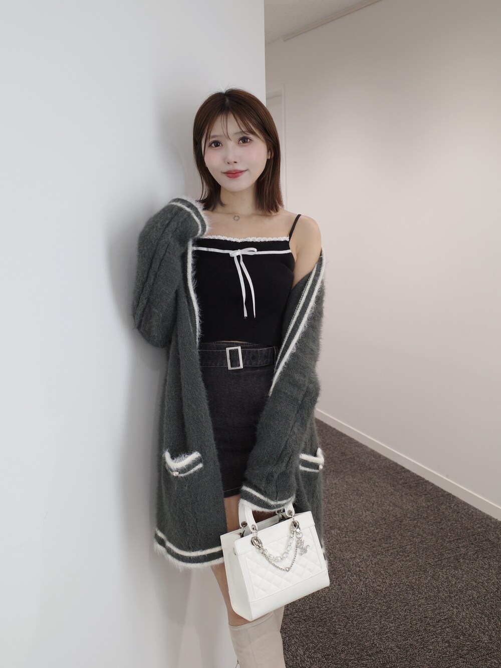 ブラック系のニット/セーター、グレー系のワンピース、ブルー系のデニムスカートを着用したレディースの秋コーディネートの2枚目の写真