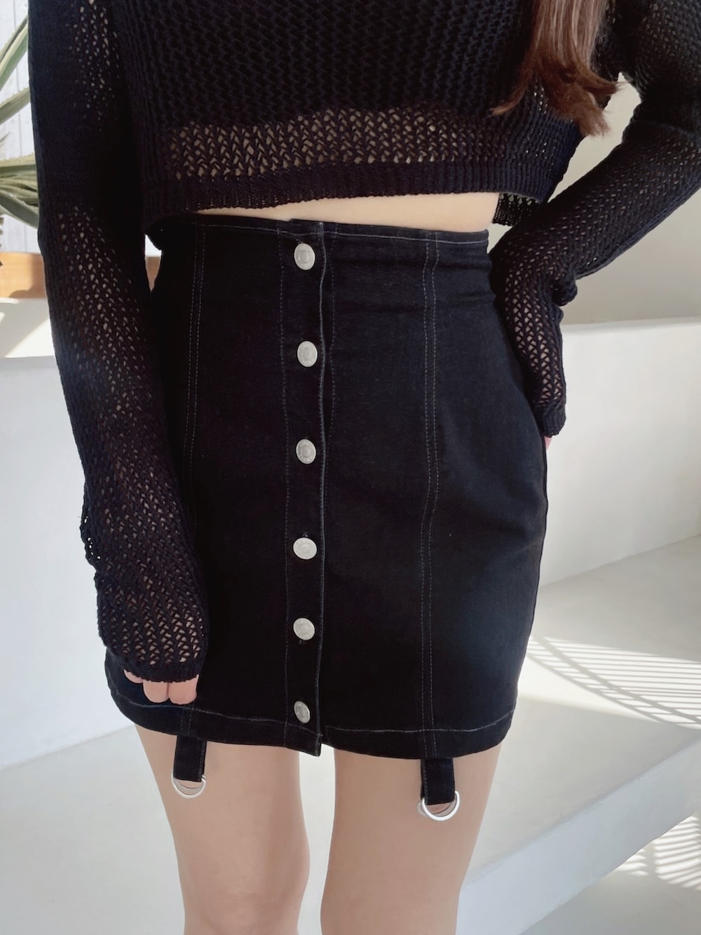 ブラック系のデニムスカート、ブラック系のサンダル、ブラック系のニット/セーターを着用したレディースの冬コーディネートの4枚目の写真