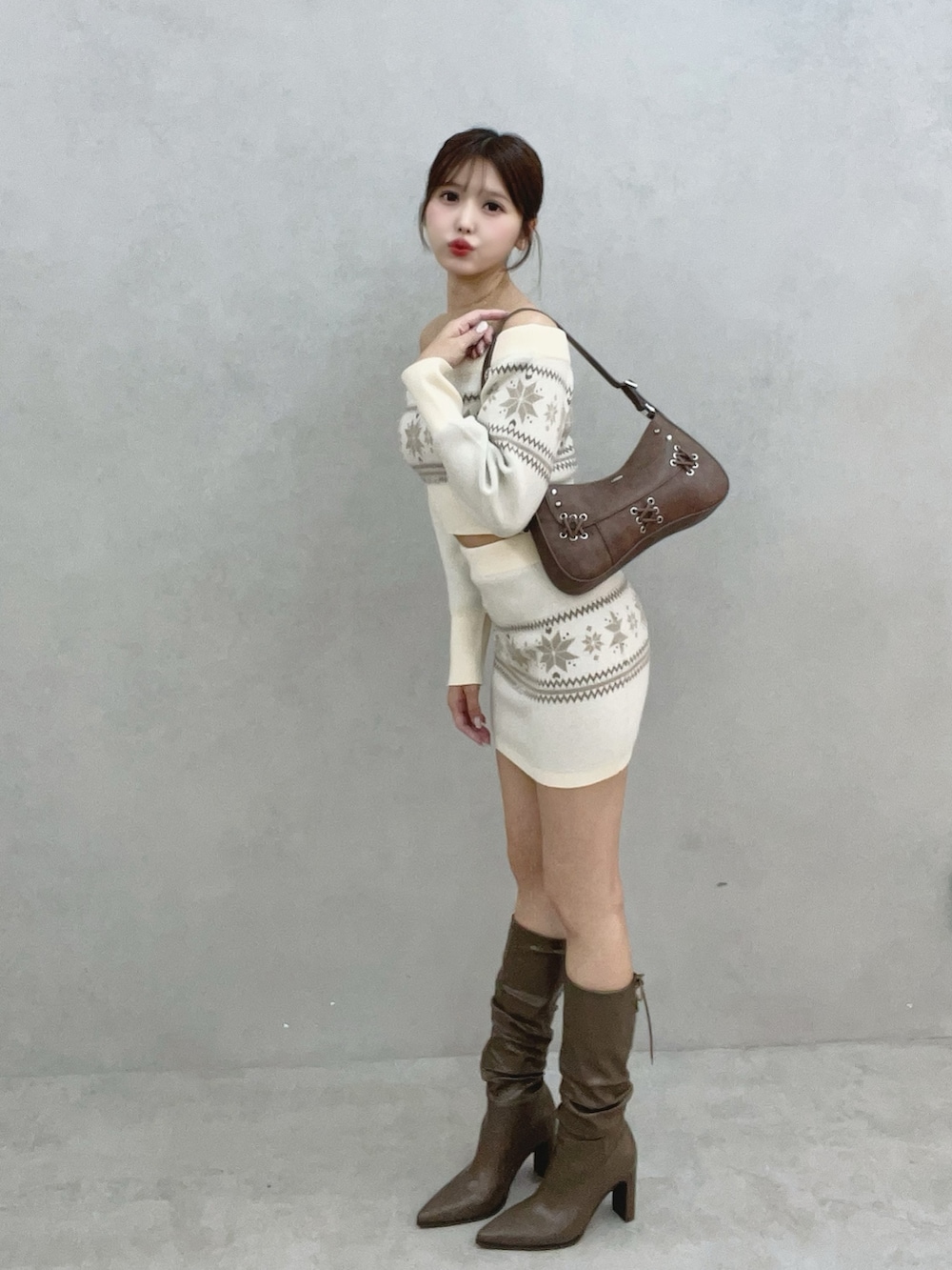 ホワイト系のニット/セーター、ホワイト系のスカート、ブラウン系のブーツを着用したレディースの秋コーディネートの3枚目の写真
