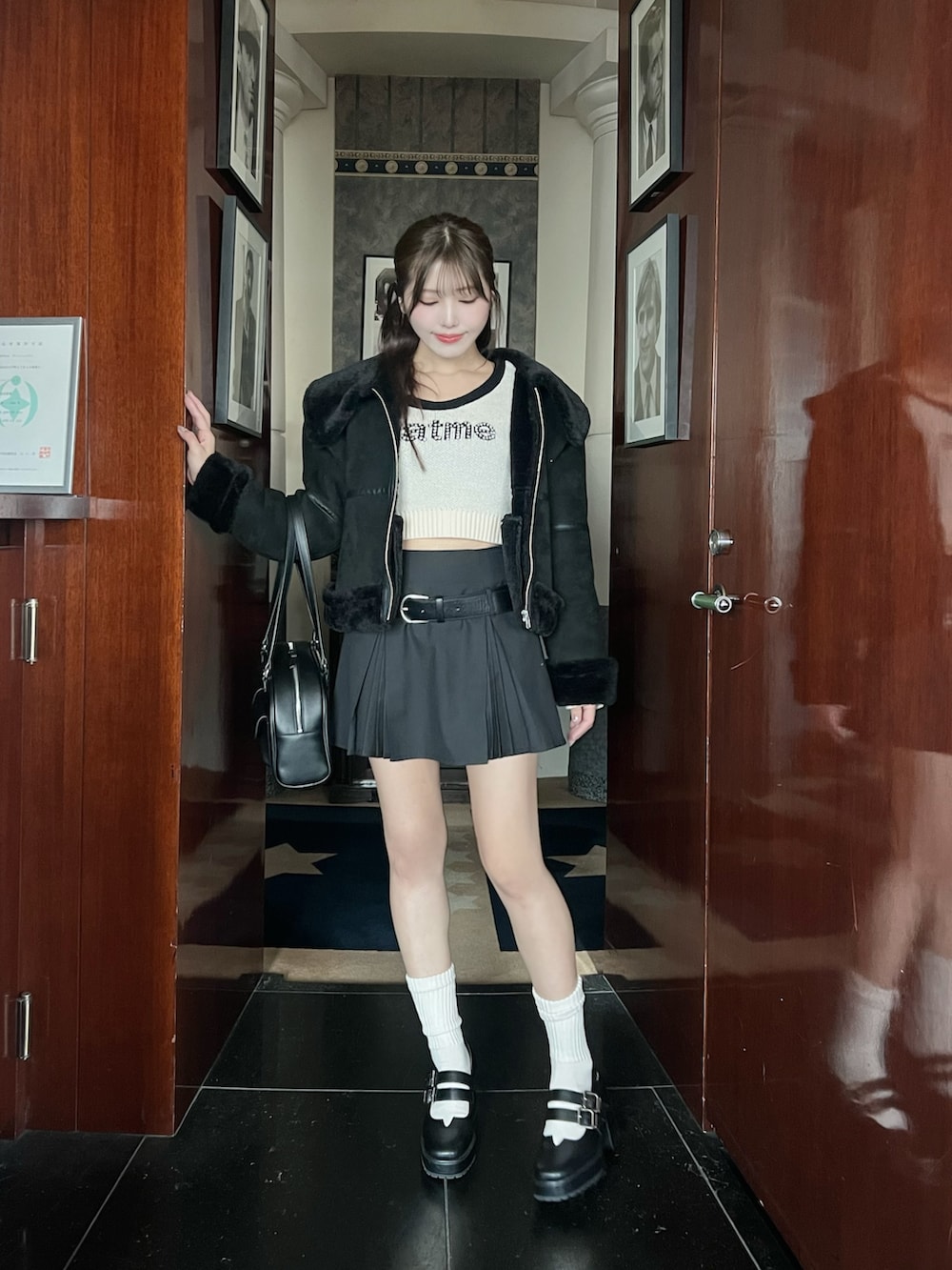 ブラック系のブルゾン、グレー系のスカート、ホワイト系のニット/セーターを着用したレディースの冬コーディネートの2枚目の写真