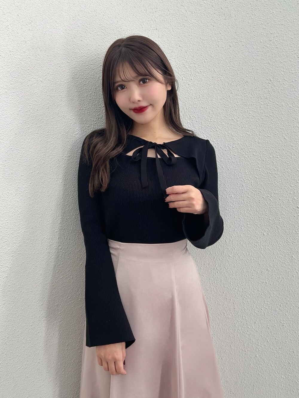 ブラック系のニット/セーター、ピンク系のスカート、ブラック系のショルダーバッグを着用したレディースの冬コーディネートの2枚目の写真