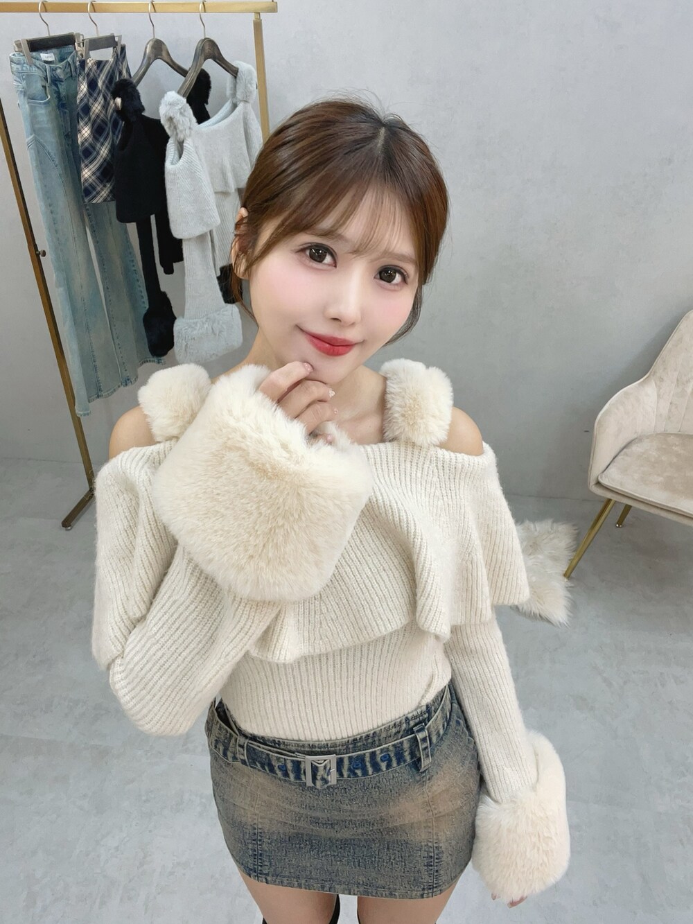 ホワイト系のニット/セーター、ブルー系のデニムスカート、ブラック系のブーツを着用したレディースの秋コーディネートの2枚目の写真