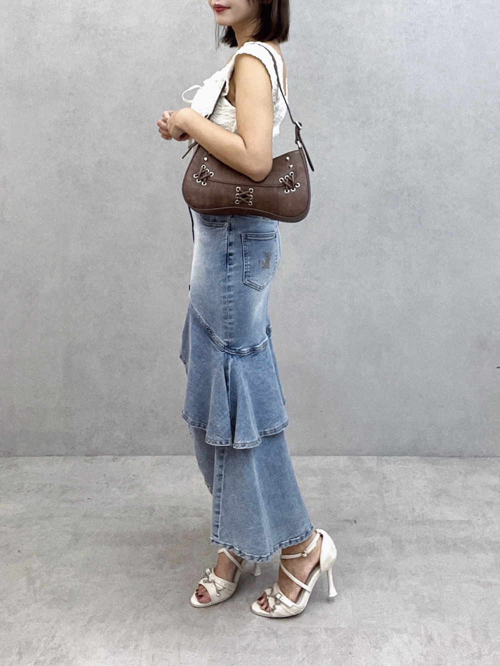 ブラウン系のショルダーバッグ、ホワイト系のTシャツ/カットソー、ブルー系のデニムスカートを着用したレディースの秋コーディネートの3枚目の写真