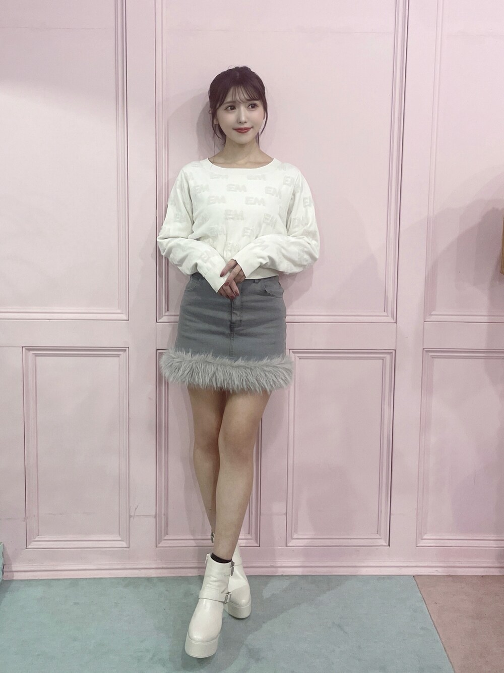 ホワイト系のニット/セーター、グレー系のデニムスカート、ホワイト系のブーツを着用したレディースの秋コーディネートの4枚目の写真