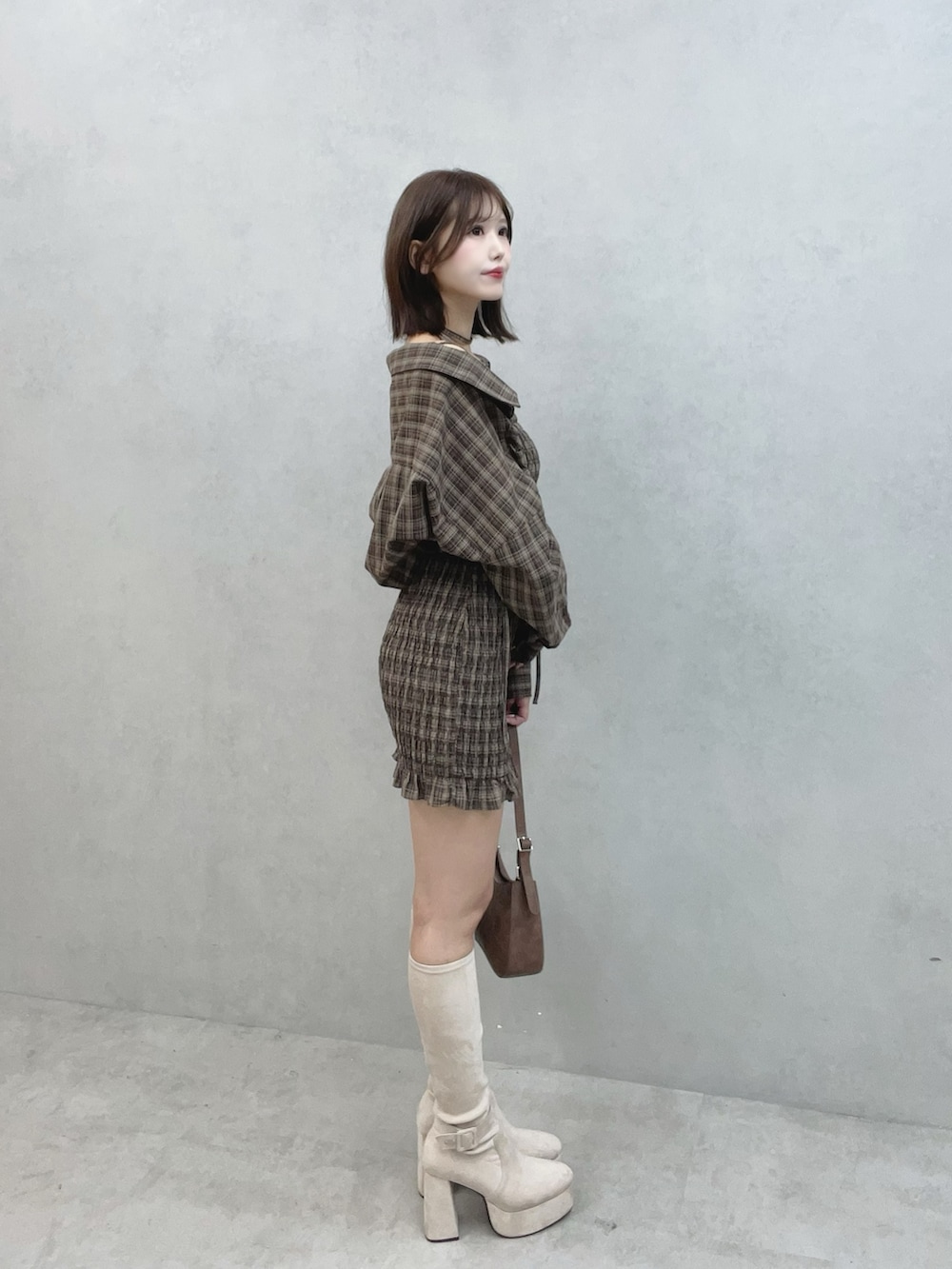 ブラウン系のワンピース、ブラウン系のショルダーバッグ、ホワイト系のブーツを着用したレディースの秋コーディネートの3枚目の写真