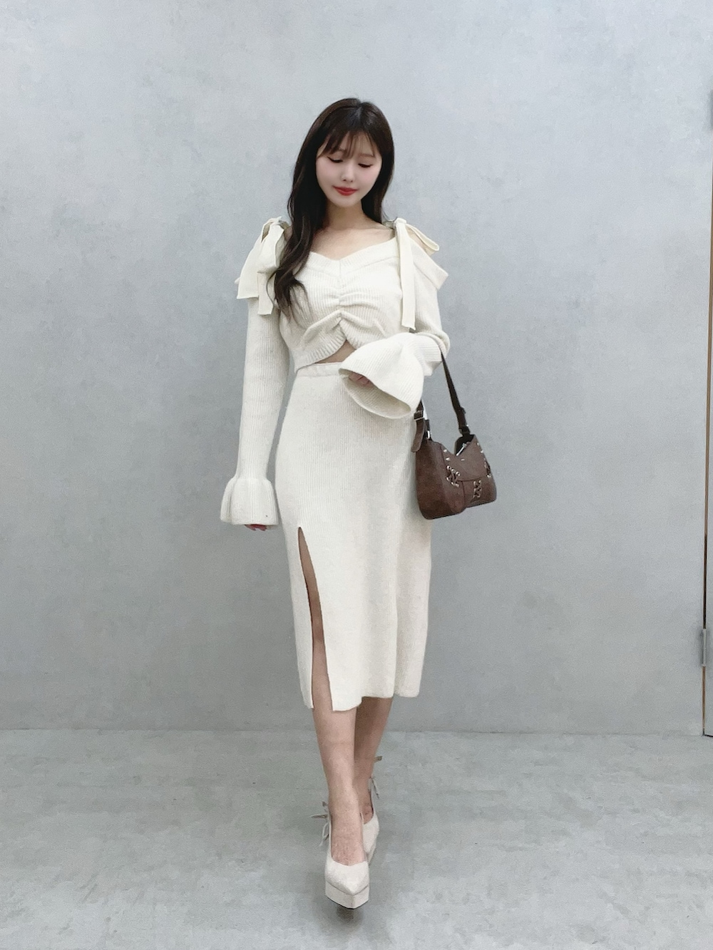 ブラウン系のショルダーバッグ、ホワイト系のワンピースを着用したレディースの冬コーディネートの2枚目の写真