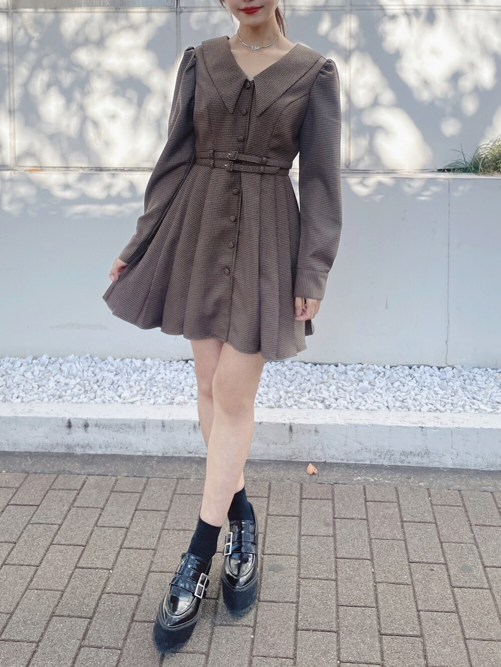 ブラウン系のワンピース、ベージュ系のその他アウター、ブラック系のローファーを着用したレディースの冬コーディネートの7枚目の写真