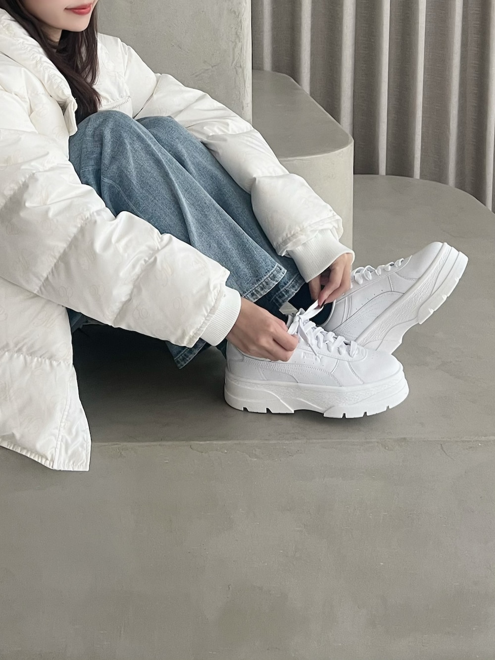ホワイト系のダウンジャケット/コート、ブルー系のデニムパンツ、ホワイト系のスニーカーを着用したレディースの秋コーディネートの2枚目の写真