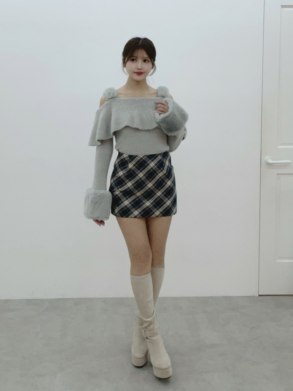 グレー系のニット/セーター、ホワイト系のブーツ、ブルー系のスカートを着用したレディースの秋コーディネートの2枚目の写真