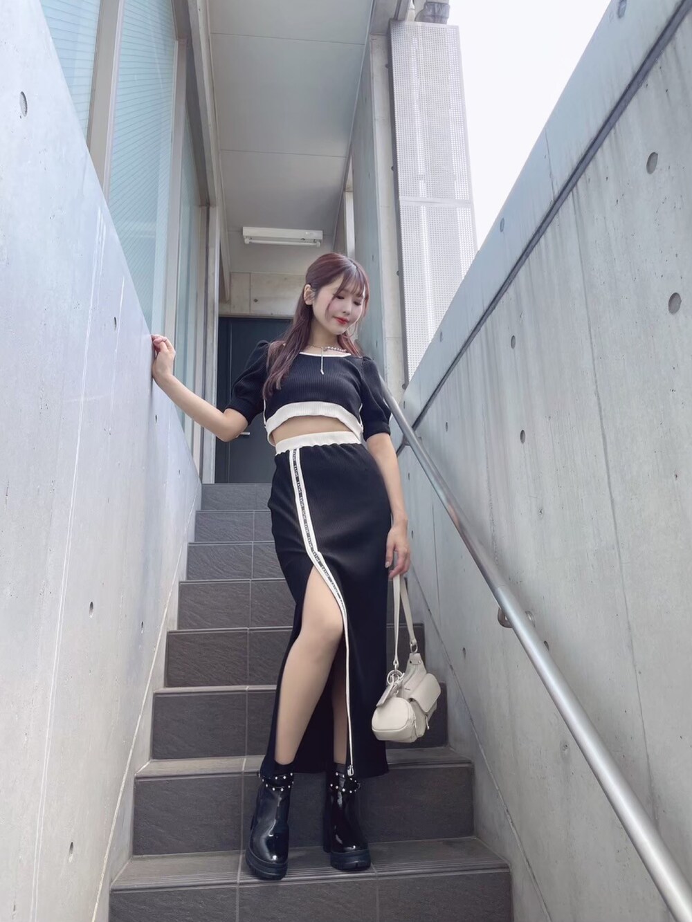 ブラック系のTシャツ/カットソー、ブラック系のスカート、ホワイト系のショルダーバッグを着用したレディースの秋コーディネートの5枚目の写真