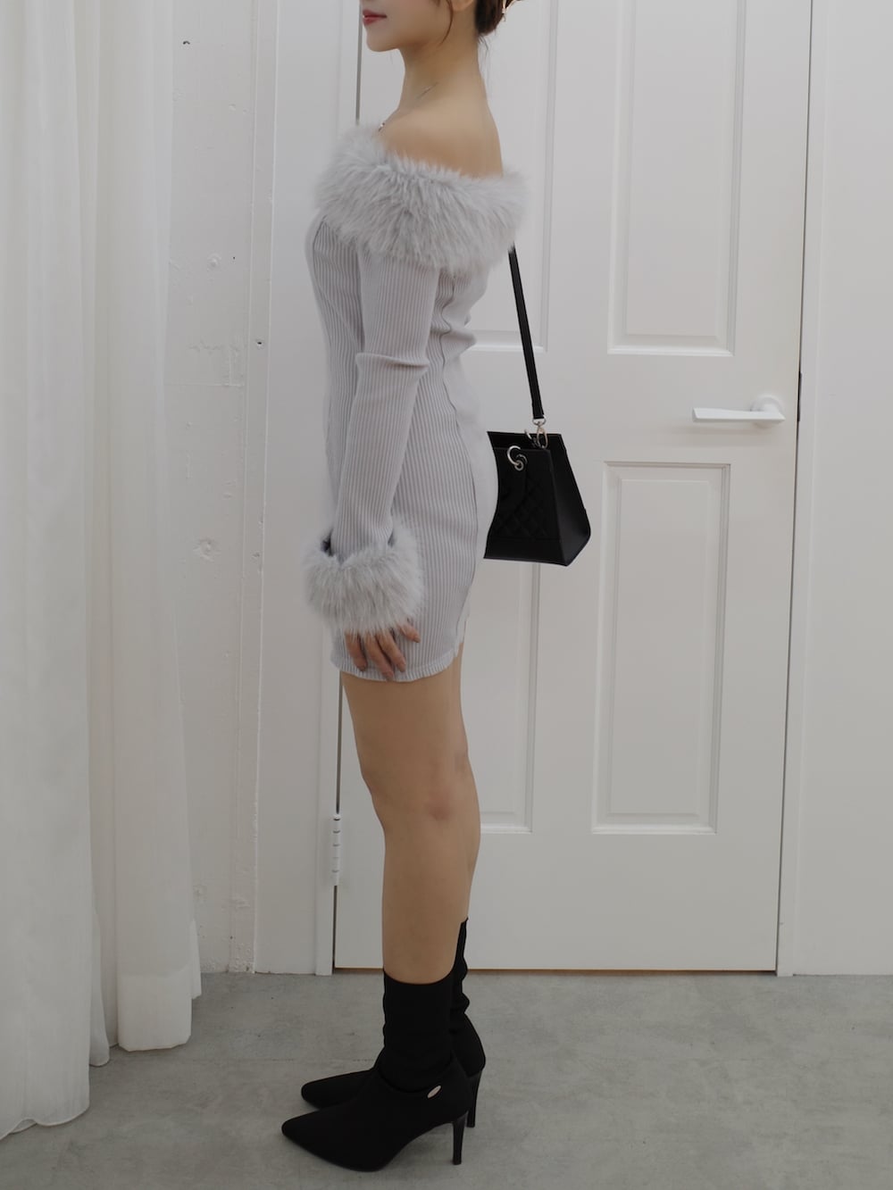 グレー系のワンピース、ブラック系のブーツ、ブラック系のハンドバッグを着用したレディースの秋コーディネートの3枚目の写真