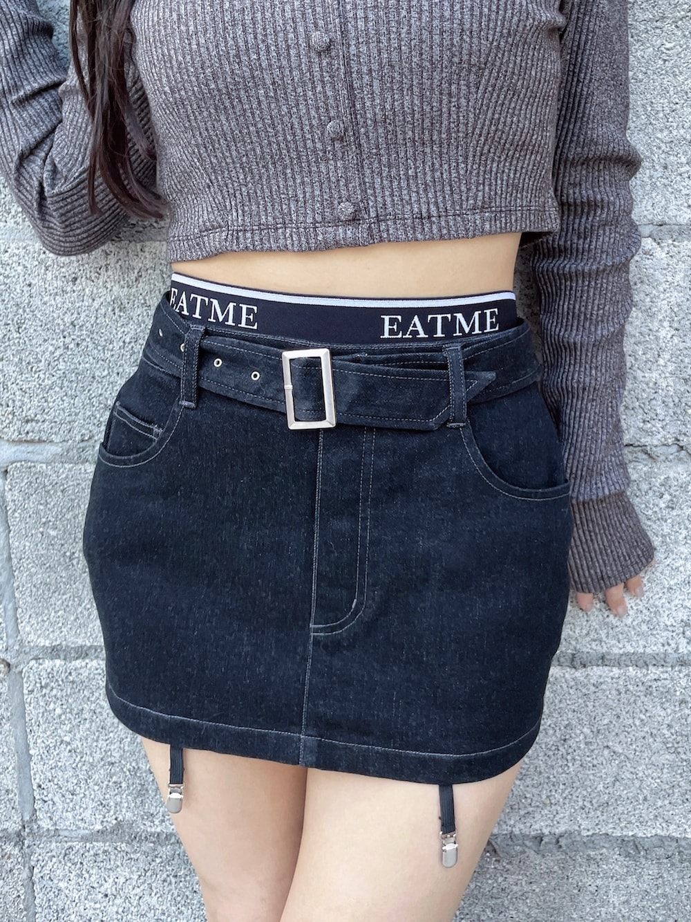 グレー系のTシャツ/カットソー、ブラック系のスカート、ブラック系のブーツを着用したレディースの秋コーディネートの5枚目の写真