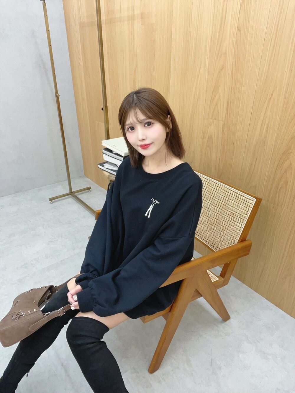 ブラック系のスウェット、ブラック系のブーツ、ブラウン系のショルダーバッグを着用したレディースの秋コーディネートの2枚目の写真