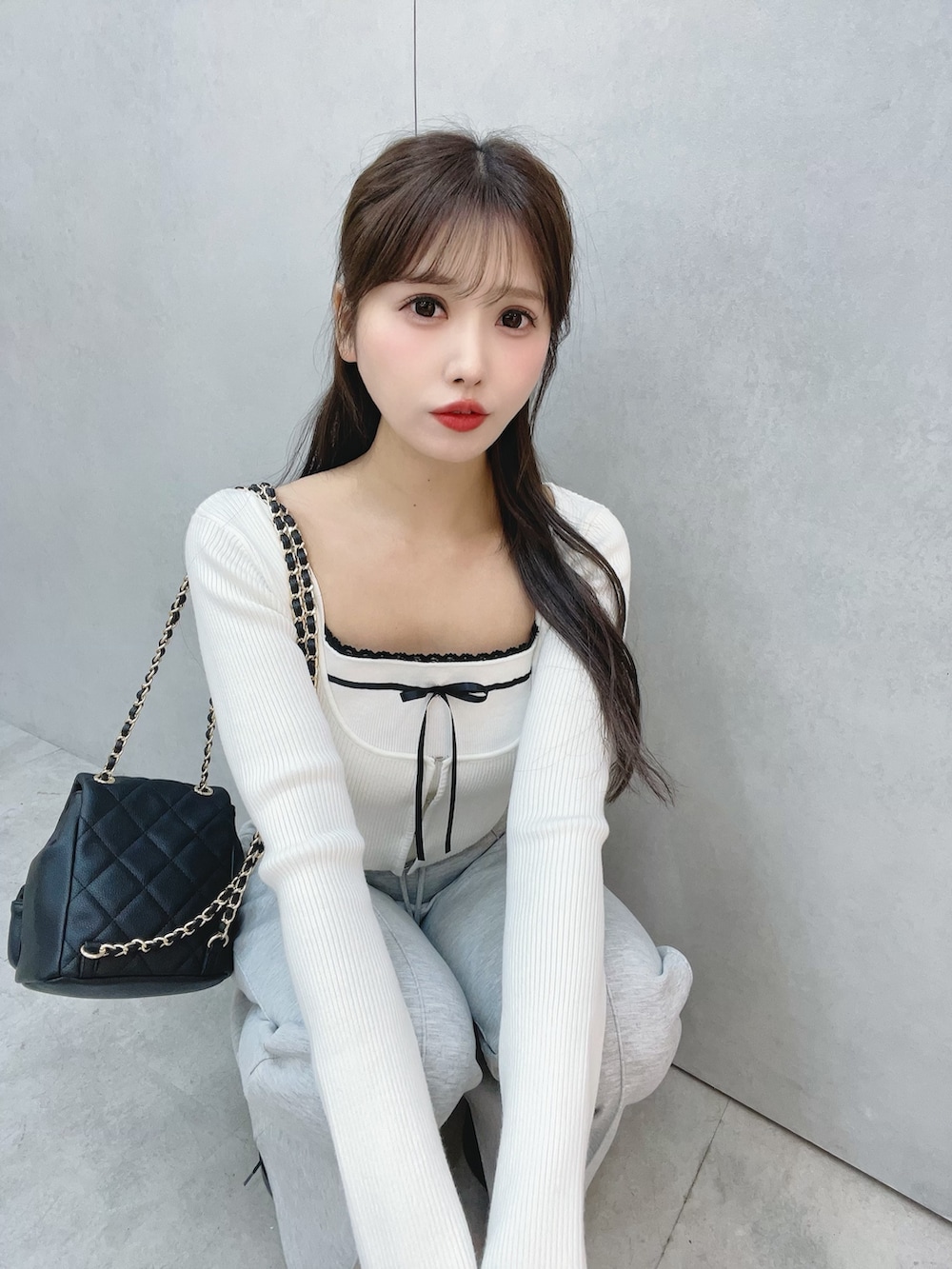 ホワイト系のニット/セーター、グレー系のその他パンツ、ブラック系のバックパック/リュックを着用したレディースの冬コーディネートの6枚目の写真