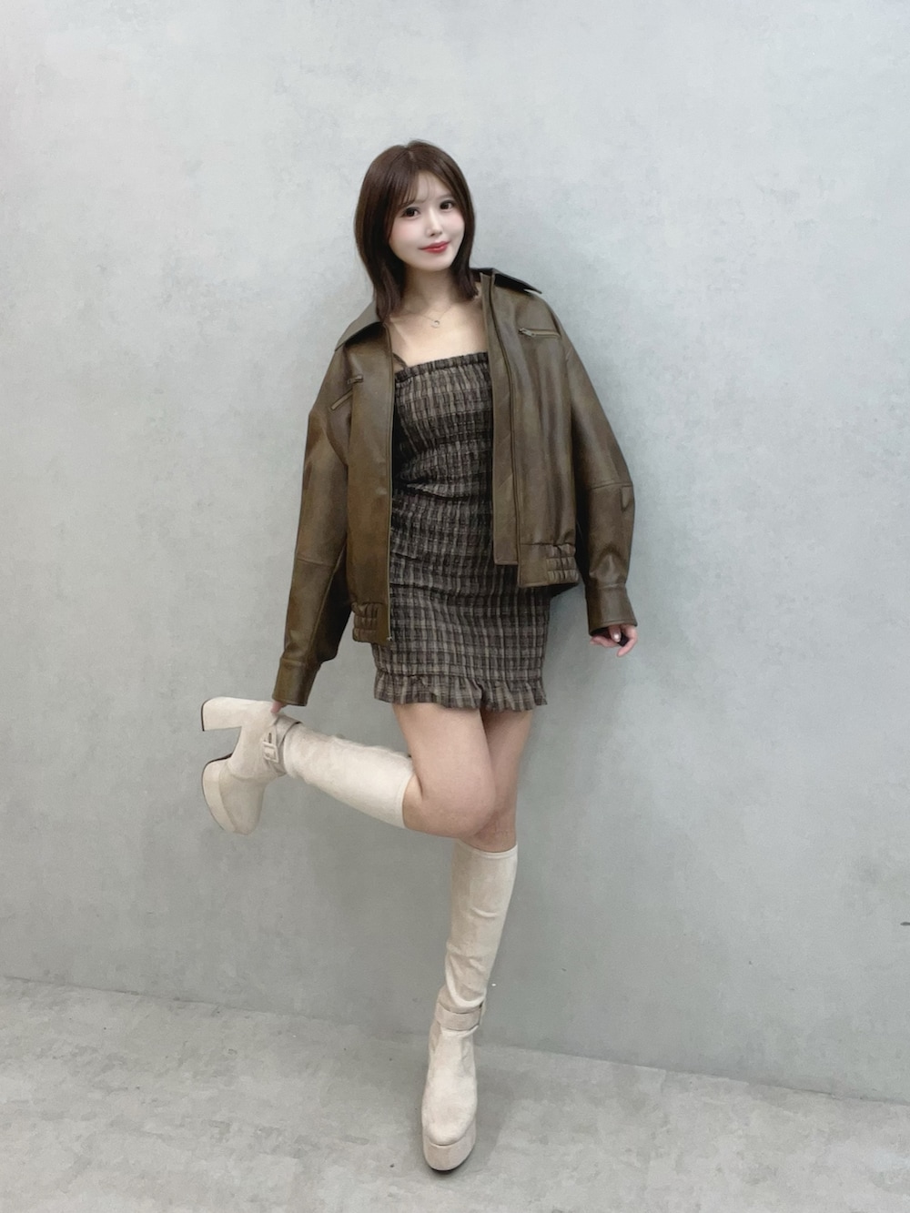 ブラウン系のワンピース、ブラウン系のブルゾン、ホワイト系のブーツを着用したレディースの秋コーディネートの2枚目の写真