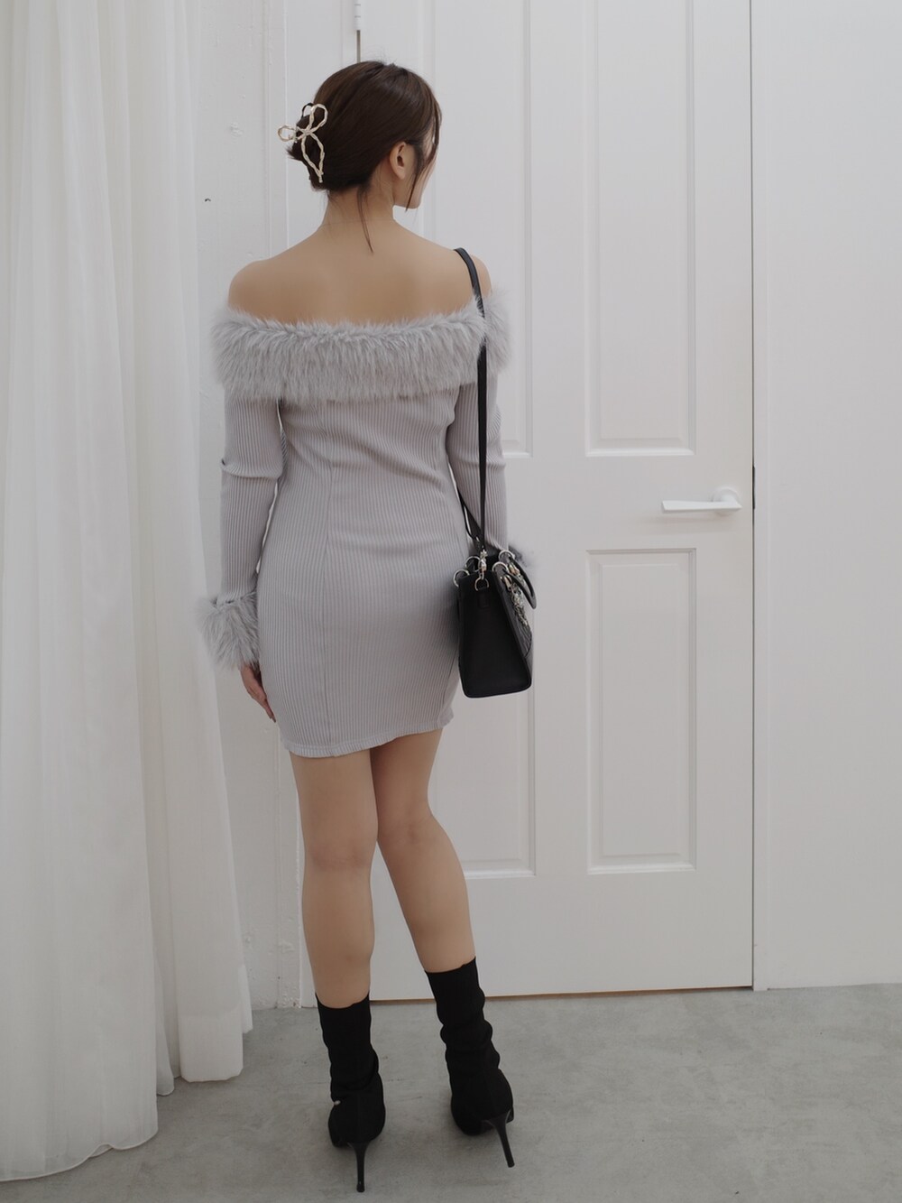 グレー系のワンピース、ブラック系のブーツ、ブラック系のハンドバッグを着用したレディースの秋コーディネートの4枚目の写真