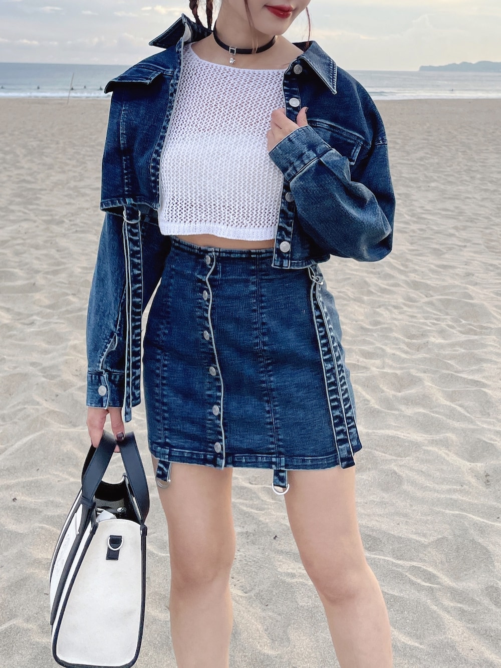 ブルー系のデニムジャケット、ブルー系のデニムスカート、ホワイト系のショルダーバッグを着用したレディースの冬コーディネートの3枚目の写真