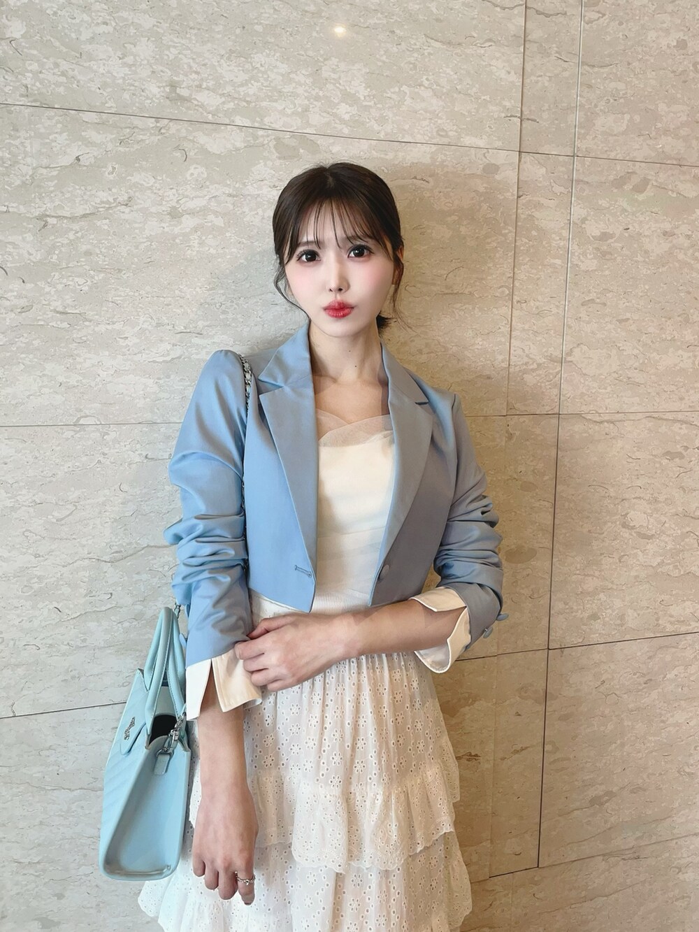 ホワイト系のスカート、ブルー系のハンドバッグ、ホワイト系のブーツを着用したレディースの春コーディネートの8枚目の写真