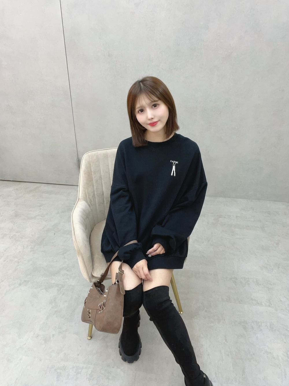 ブラック系のスウェット、ブラック系のブーツ、ブラウン系のショルダーバッグを着用したレディースの秋コーディネートの3枚目の写真