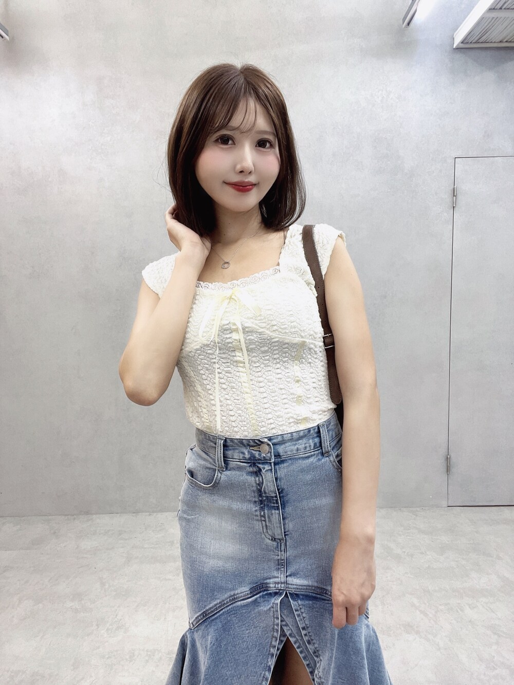 ブラウン系のショルダーバッグ、ホワイト系のTシャツ/カットソー、ブルー系のデニムスカートを着用したレディースの秋コーディネートの5枚目の写真