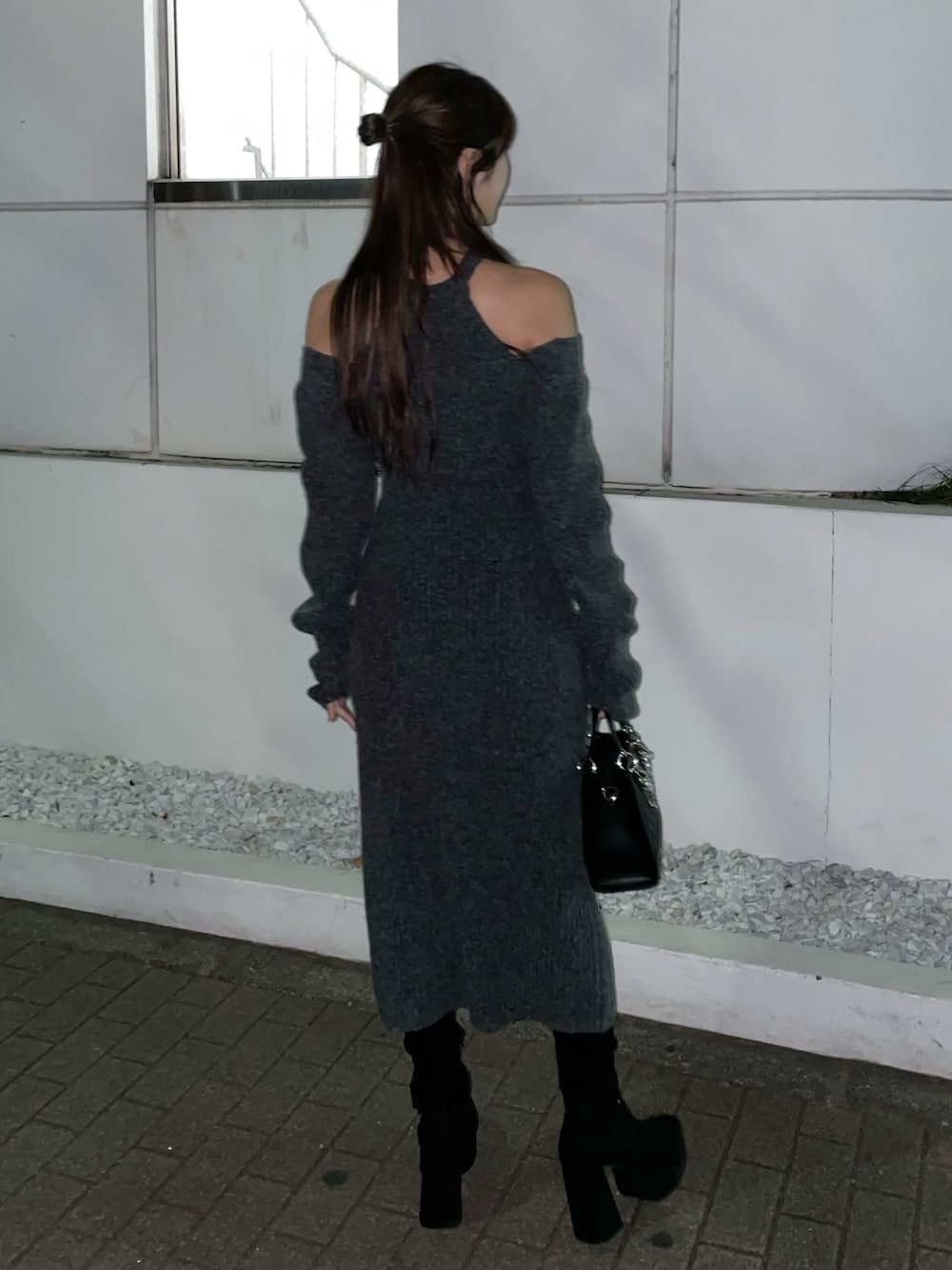 グレー系のワンピース、ブラック系のハンドバッグ、ブラック系のブーツを着用したレディースの冬コーディネートの6枚目の写真