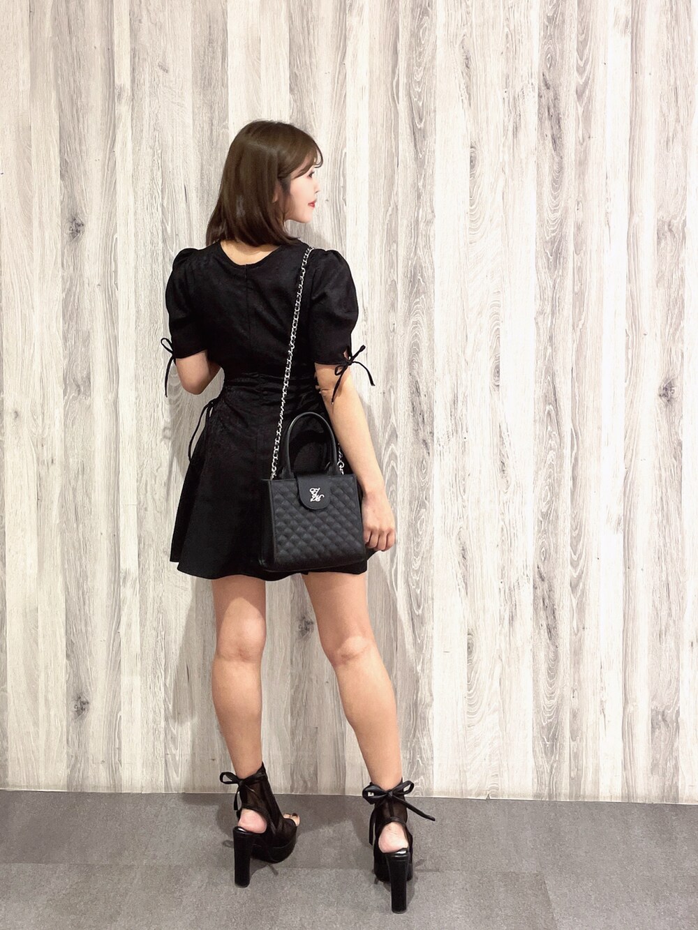 ブラック系のサンダル、ブラック系のハンドバッグ、ブラック系のワンピースを着用したレディースの春コーディネートの4枚目の写真