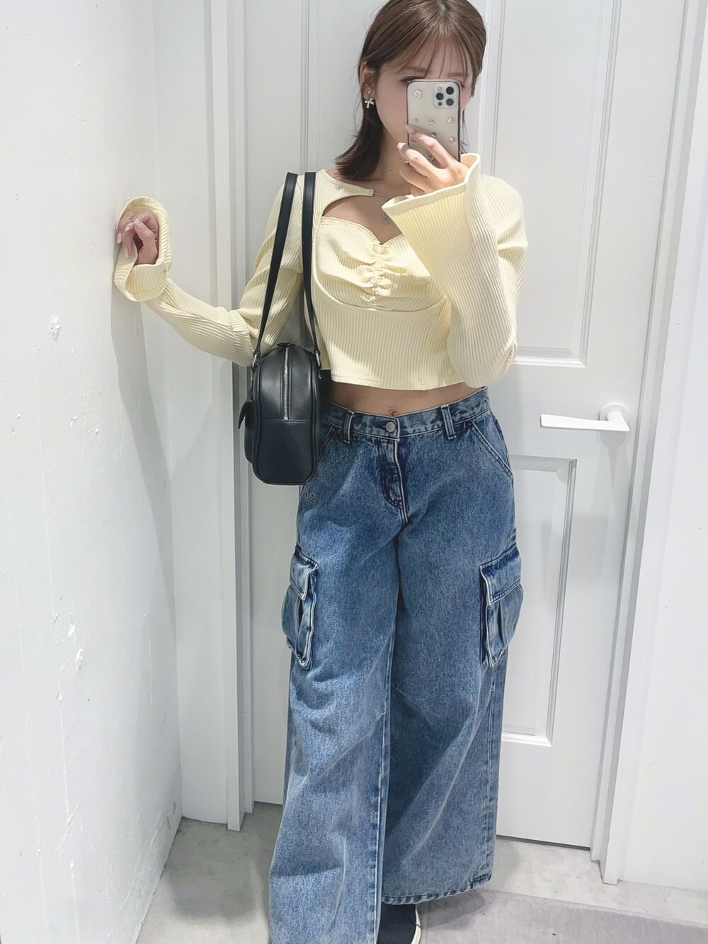 イエロー系のTシャツ/カットソー、ブルー系のデニムパンツ、ブラック系のボストンバッグを着用したレディースの冬コーディネートの4枚目の写真