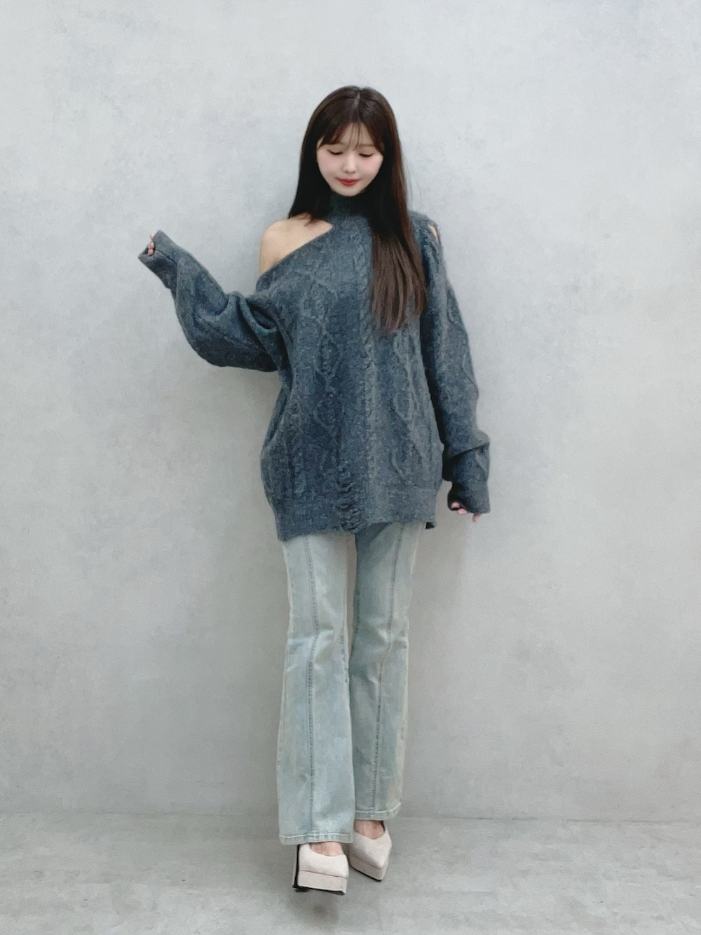 グレー系のニット/セーター、ブルー系のデニムパンツを着用したレディースの冬コーディネートの2枚目の写真