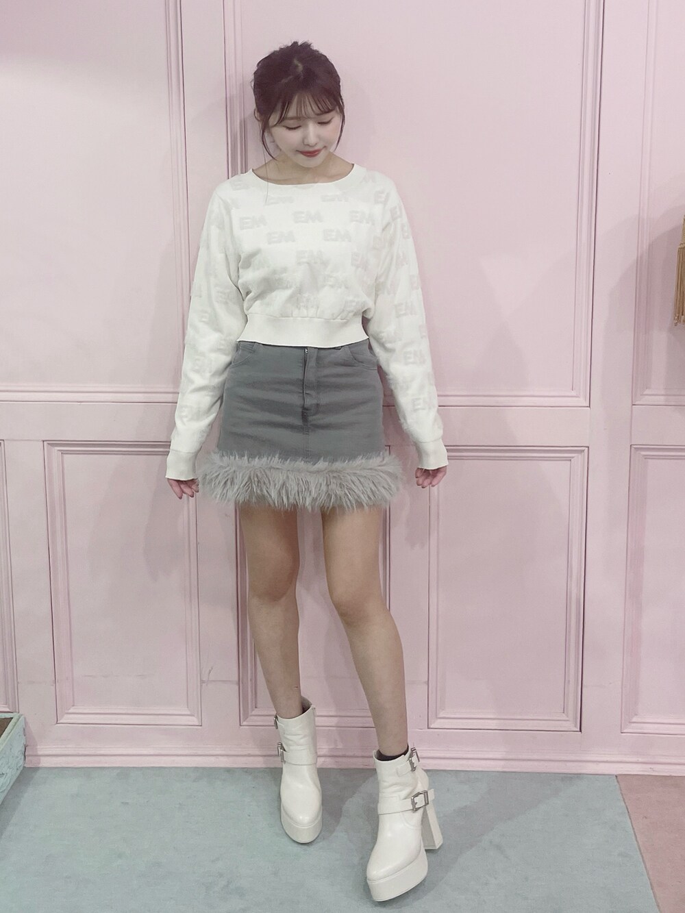 ホワイト系のニット/セーター、グレー系のデニムスカート、ホワイト系のブーツを着用したレディースの秋コーディネートの5枚目の写真