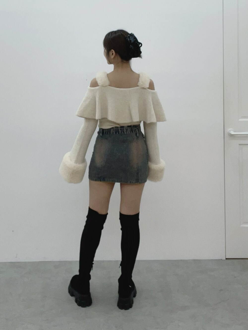 ホワイト系のニット/セーター、ブルー系のデニムスカート、ブラック系のブーツを着用したレディースの秋コーディネートの6枚目の写真