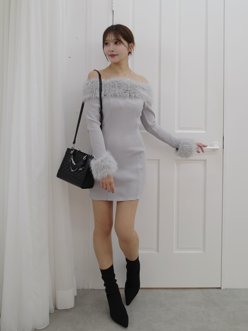 グレー系のワンピース、ブラック系のブーツ、ブラック系のハンドバッグを着用したレディースの秋コーディネートの2枚目の写真