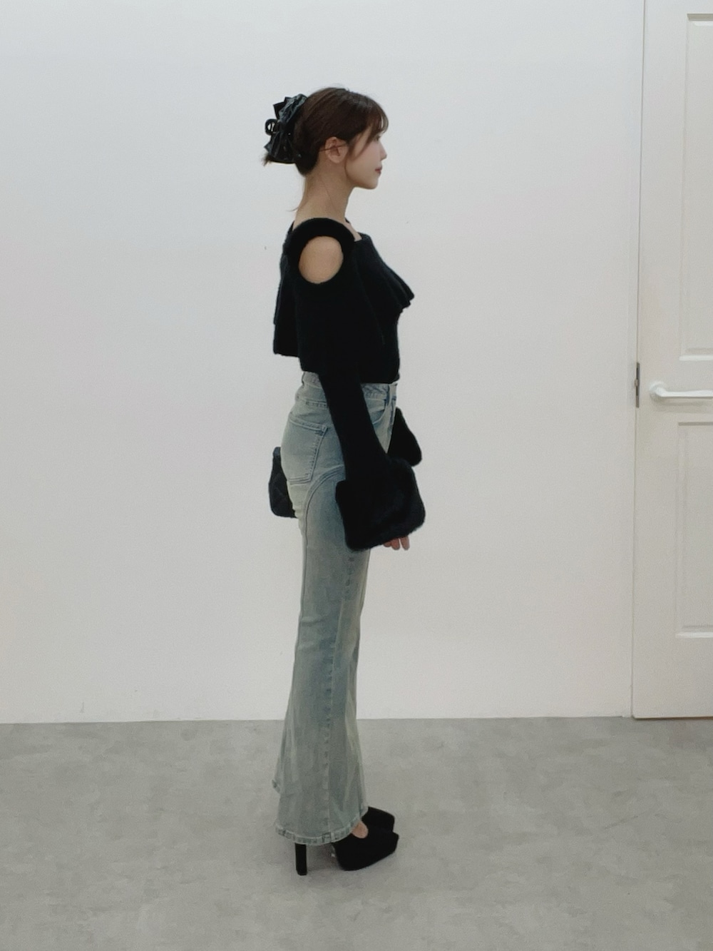 ブラック系のハンドバッグ、ブルー系のデニムパンツ、ブラック系のニット/セーターを着用したレディースの秋コーディネートの4枚目の写真