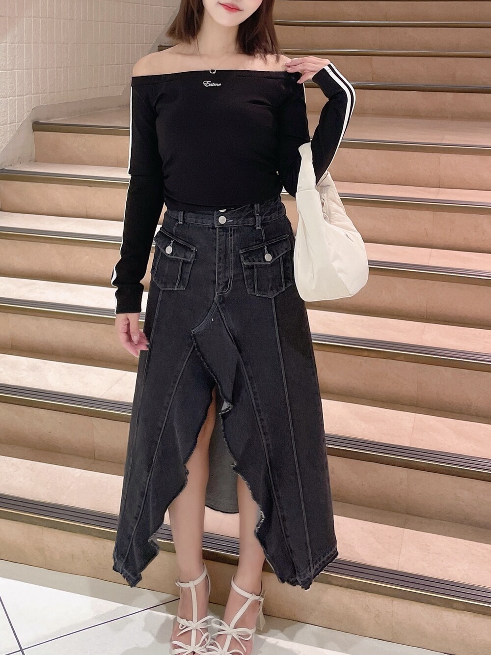 ブラック系のTシャツ/カットソー、ブラック系のデニムスカート、ホワイト系のハンドバッグを着用したレディースの春コーディネートの3枚目の写真