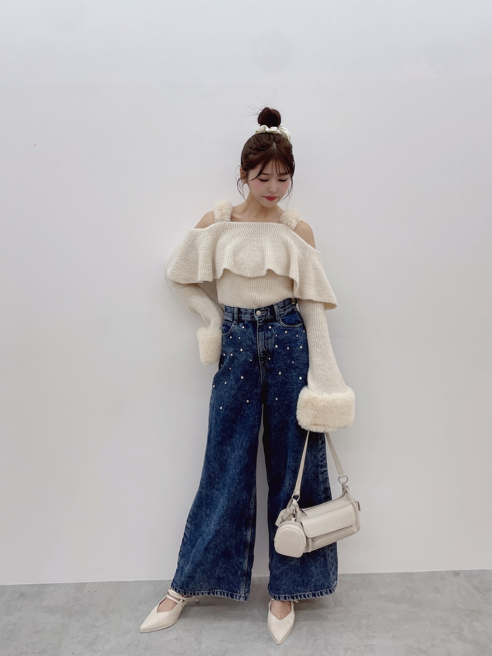 ホワイト系のニット/セーター、ブルー系のデニムパンツ、ホワイト系のパンプスを着用したレディースの秋コーディネートの2枚目の写真