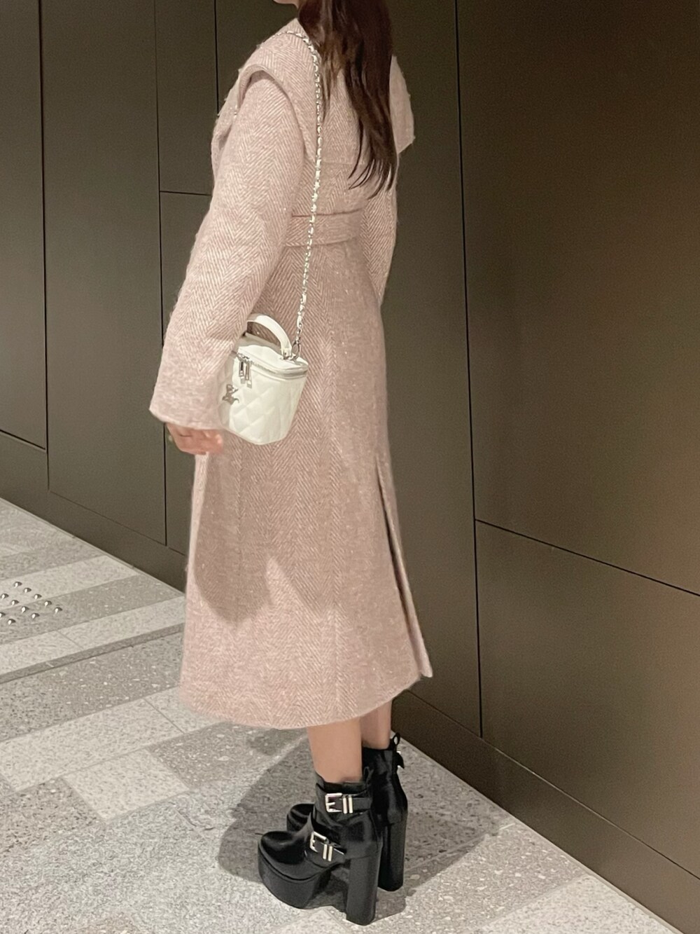 ホワイト系のハンドバッグ、ピンク系のチェスターコート、ブラック系のブーツを着用したレディースの冬コーディネートの3枚目の写真
