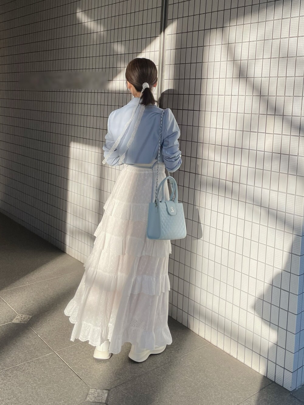 ホワイト系のスカート、ブルー系のハンドバッグ、ホワイト系のブーツを着用したレディースの春コーディネートの7枚目の写真