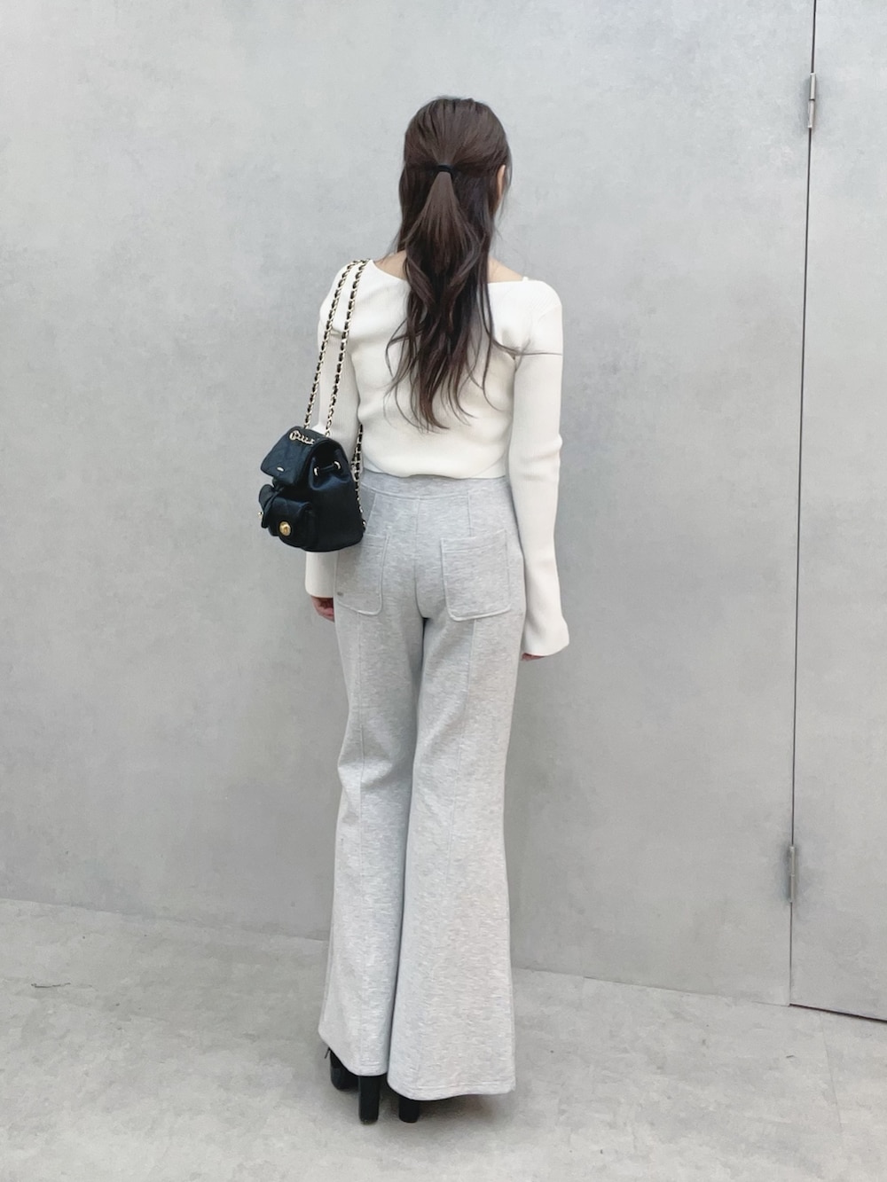 ホワイト系のニット/セーター、グレー系のその他パンツ、ブラック系のバックパック/リュックを着用したレディースの冬コーディネートの5枚目の写真