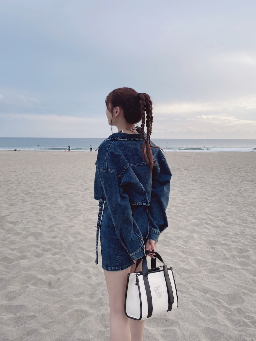 ブルー系のデニムジャケット、ブルー系のデニムスカート、ホワイト系のショルダーバッグを着用したレディースの冬コーディネートの4枚目の写真